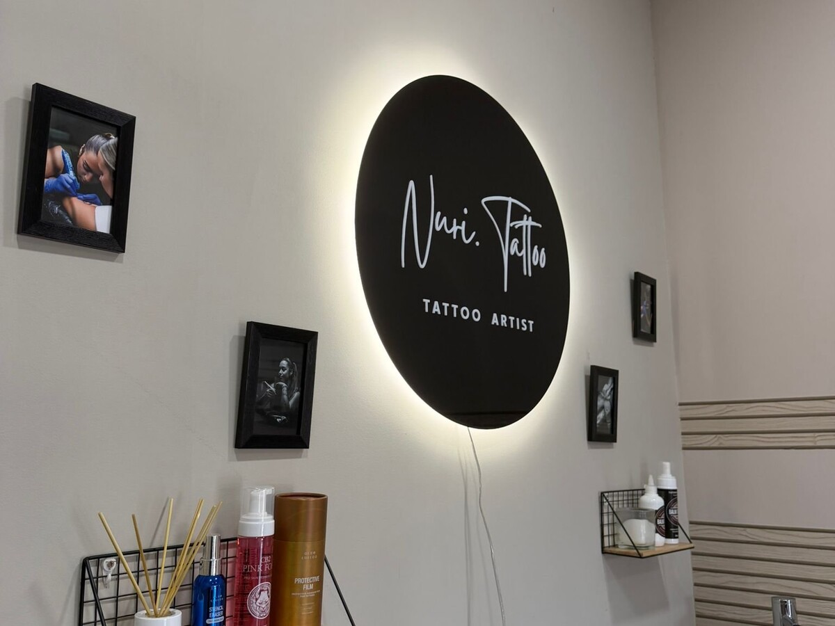 Logotipo iluminado Nuri.tattoo en el interior del estudio